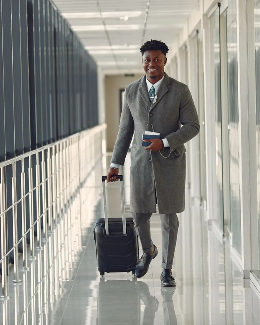 African man walking through an airport with his suitcase and passport